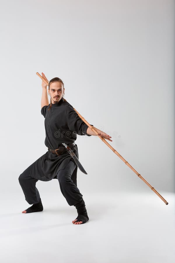 Un Homme, Dans Un Kimono Noir Pratique La Technique D'arts Martiaux Avec Un  Long Bâton De Combat En Bambou Photo stock - Image du complètement,  flexibilité: 106320478