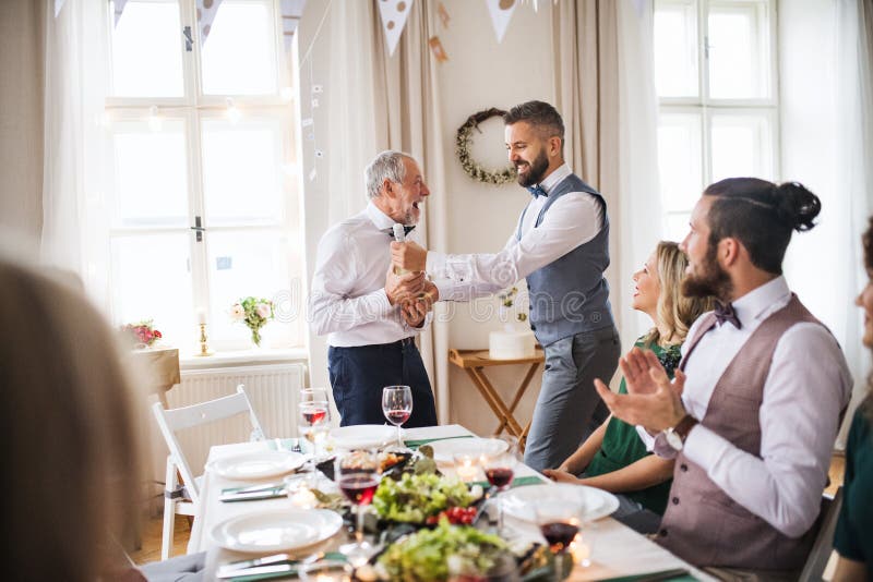 Un homme donnant une bouteille de vin à son père sur la fête d'anniversaire d'intérieur, un concept de célébration photo stock Un homme donnant une bouteille de vin à son père sur la fête d'anniversaire d'intérieur, un concept de célébration photo stock