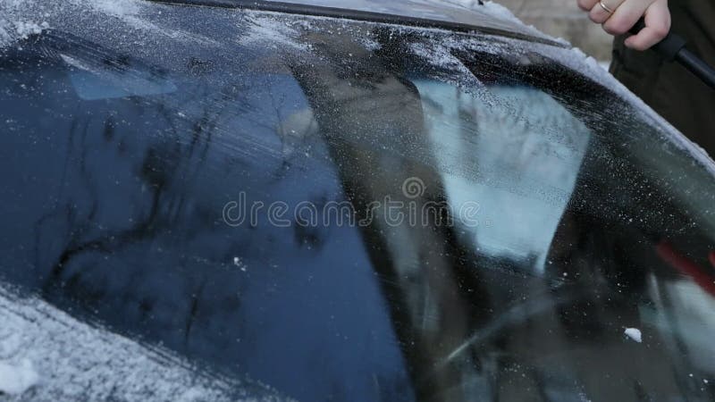 L'homme Nettoie Une Vitre Glacée Sur Une Voiture Avec Un Grattoir