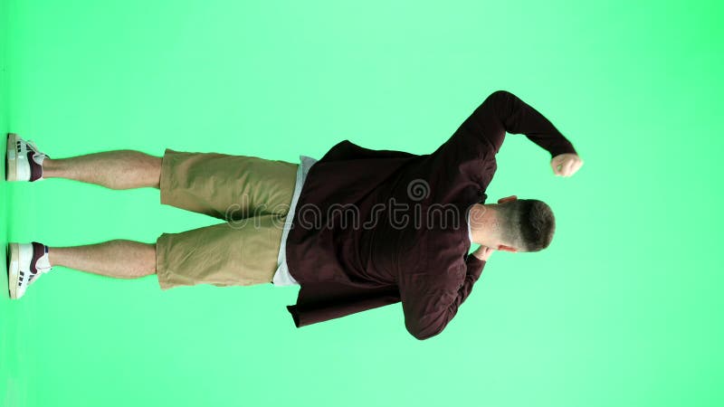 Un homme en chemise marron sur fond vert en pleine hauteur se réjouit