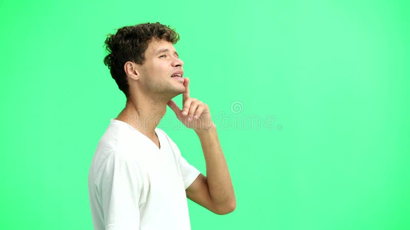 Un homme en T-shirt blanc sur un fond vert closeuse penser