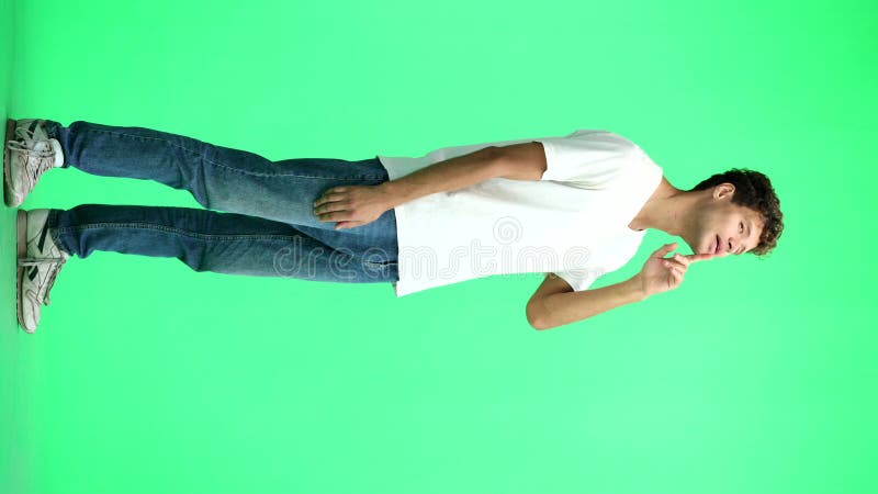 Un homme en T-shirt blanc sur fond vert en pleine hauteur pense