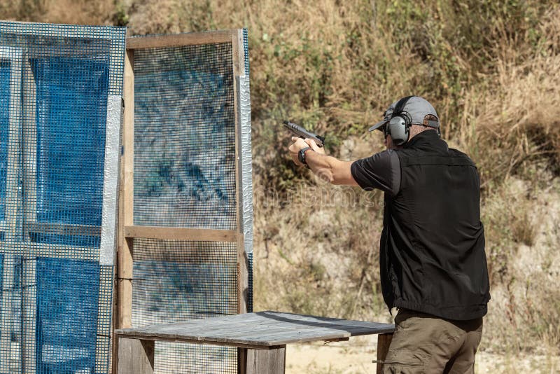 Homme en vêtements tactiques tirant à partir d'un pistolet, en rechargeant  le pistolet et en visant la cible dans la gamme de tir à porte ouverte  Photo Stock - Alamy