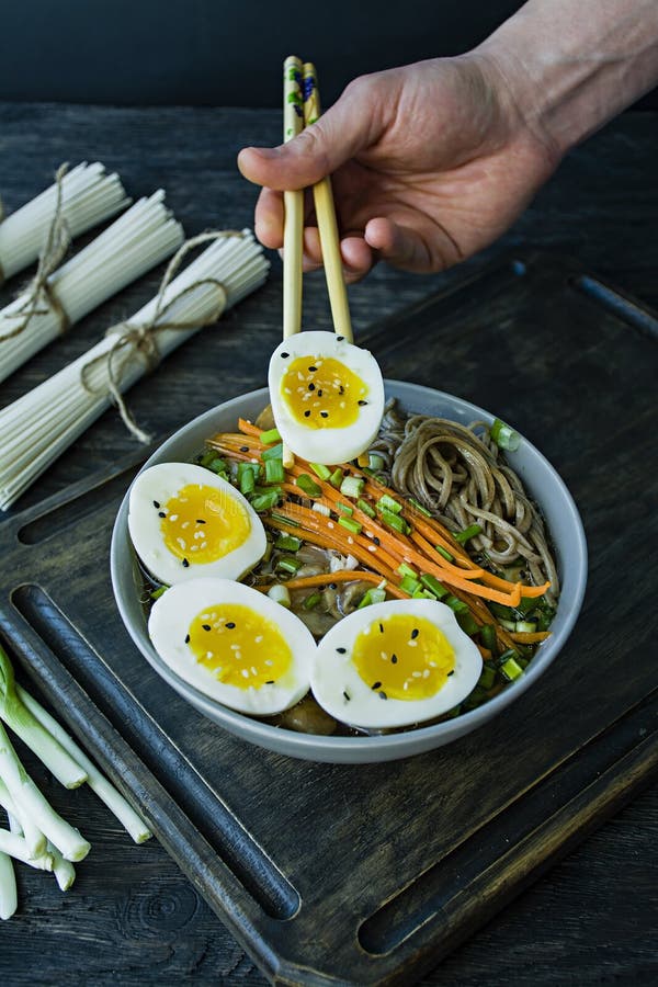 Un homme mange des nouilles de soba de sarrasin avec de la sauce et des garnitures en bouillon Nourriture japonaise Cuisine asiat photo stock Un homme mange des nouilles de soba de sarrasin avec de la sauce et des garnitures en bouillon Nourriture japonaise Cuisine asiat photo stock