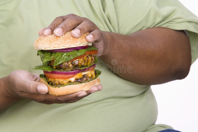 Un homme obèse tenant l'hamburger photographie stock libre de droits Un homme obèse tenant l'hamburger photographie stock libre de droits
