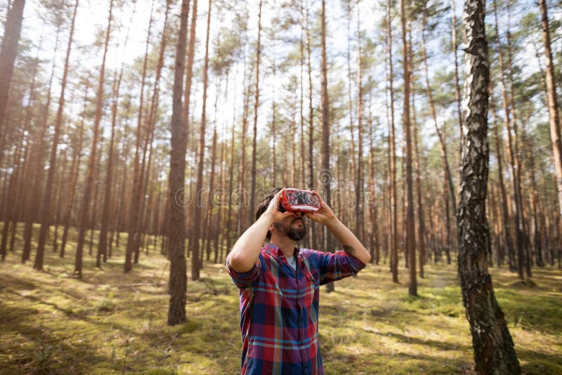 Un Homme Portant Un Simulateur De Réalité Virtuelle En Se Tenant Dans La Forêt. Un Jeune Homme Portant Un Simulateur De Réalité Virtuel Alors Qu'Il Se Trouve Dans La Forêt