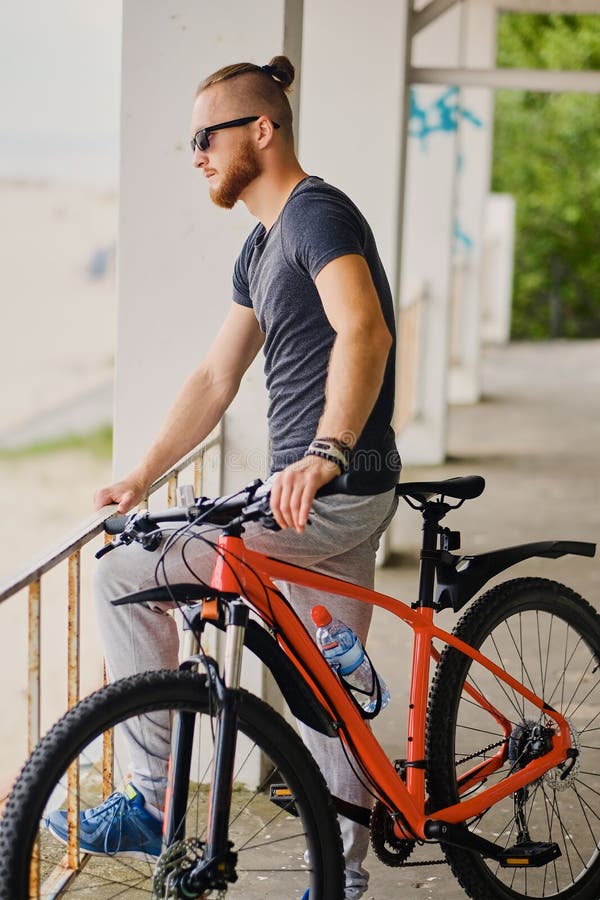 Un homme s'assied sur une bicyclette rouge de montagne extérieure photo libre de droits