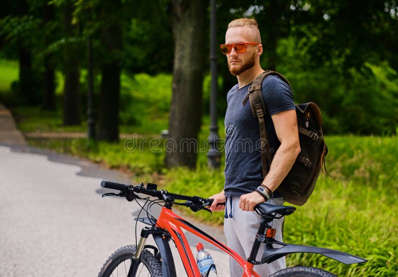 Un homme s'assied sur une bicyclette rouge de montagne extérieure photos stock