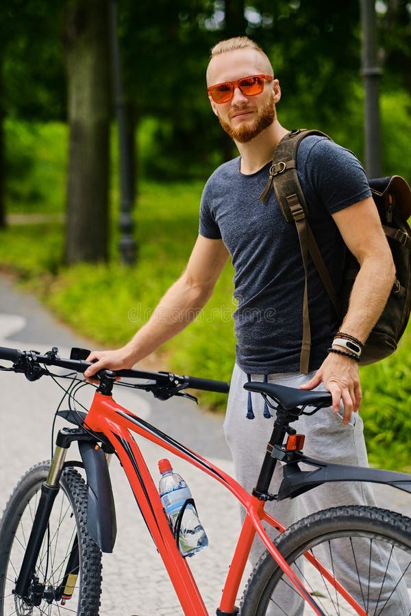 Un homme s'assied sur une bicyclette rouge de montagne extérieure photo stock