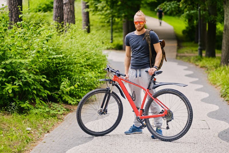 Un homme s'assied sur une bicyclette rouge de montagne extérieure photographie stock