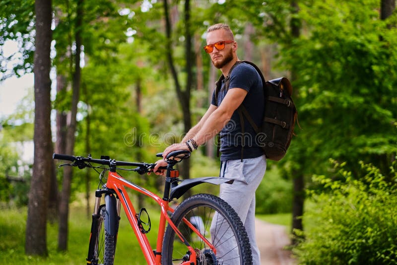 Un homme s'assied sur une bicyclette rouge de montagne extérieure photos stock