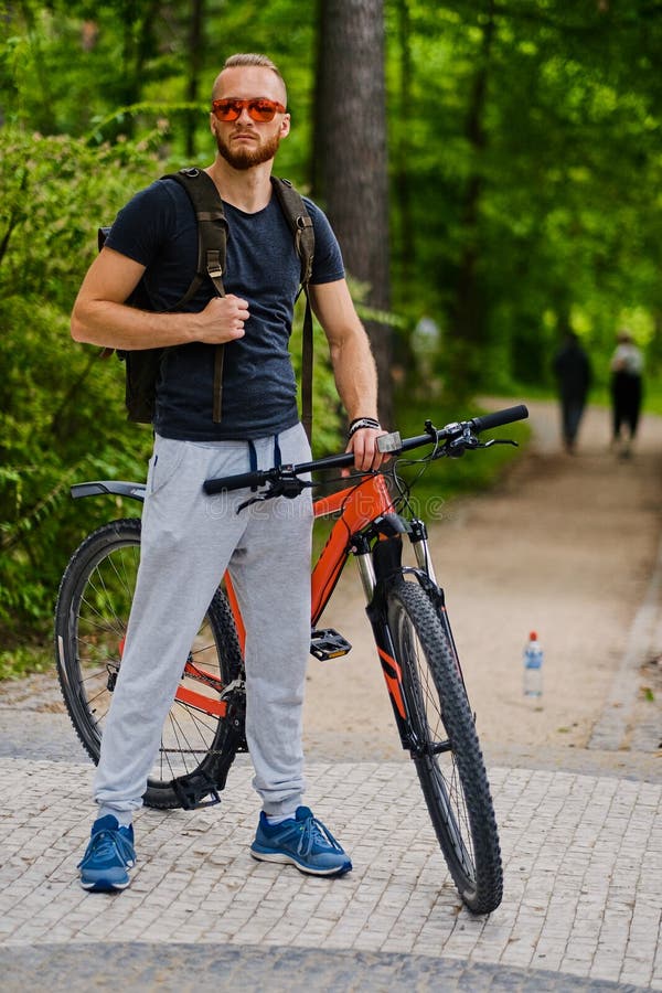 Un homme s'assied sur une bicyclette rouge de montagne extérieure images stock