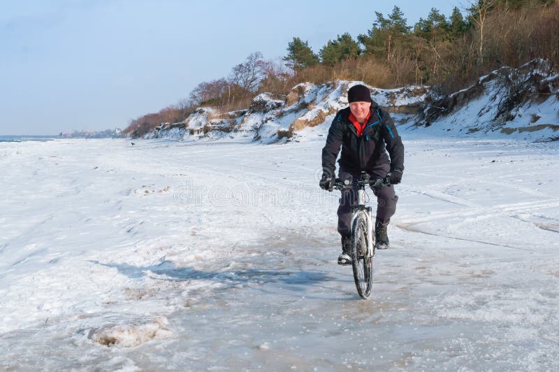 Un homme sur un vélo monte en hiver, tours de cycliste sur la neige photos stock Un homme sur un vélo monte en hiver, tours de cycliste sur la neige photos stock