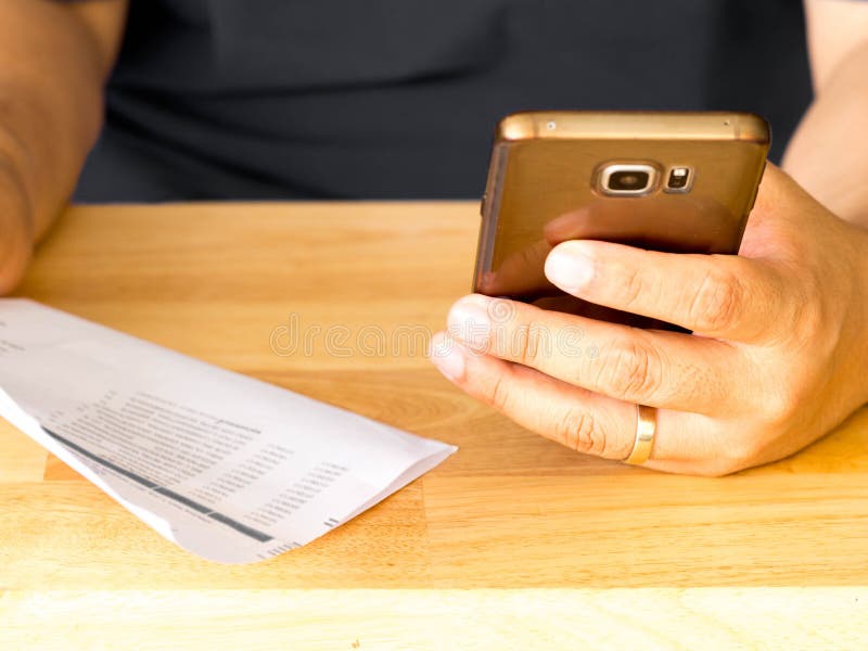 Un homme tenant le téléphone intelligent pour l'usage des opérations bancaires en ligne APP pour payer la facture de carte de cré photographie stock Un homme tenant le téléphone intelligent pour l'usage des opérations bancaires en ligne APP pour payer la facture de carte de cré photographie stock