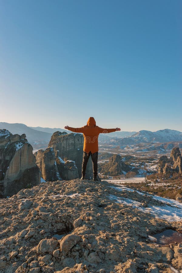 Un homme tient sur les montagnes rocheuses et apprécie la belle vue du monastère de Meteora en Grèce image libre de droits Un homme tient sur les montagnes rocheuses et apprécie la belle vue du monastère de Meteora en Grèce image libre de droits