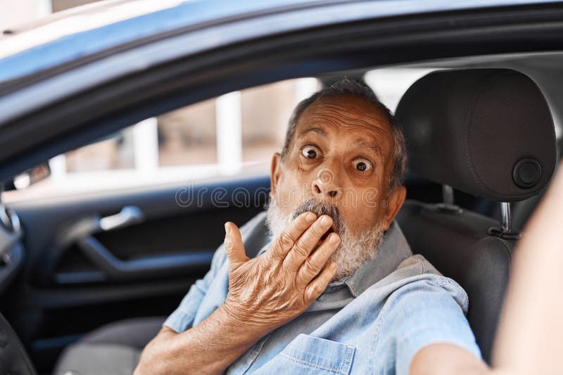 Un homme âgé choqué couvre la bouche par surprise en faisant un selfie en voiture images stock
