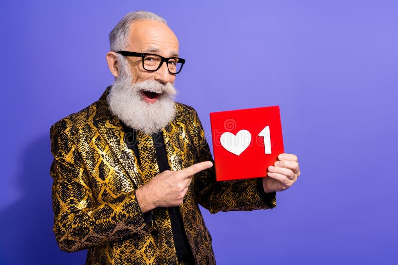 Un homme âgé dans une veste d'or vibrante tenant un symbole cardiaque sur fond violet photos libres de droits