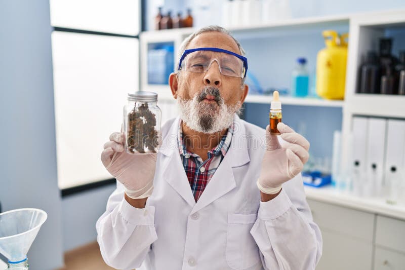 Un homme âgé joyeux qui fait face au poisson dans la folie joyeuse au labo créer des yeux fous et la bouche comique tout en tenant photo libre de droits