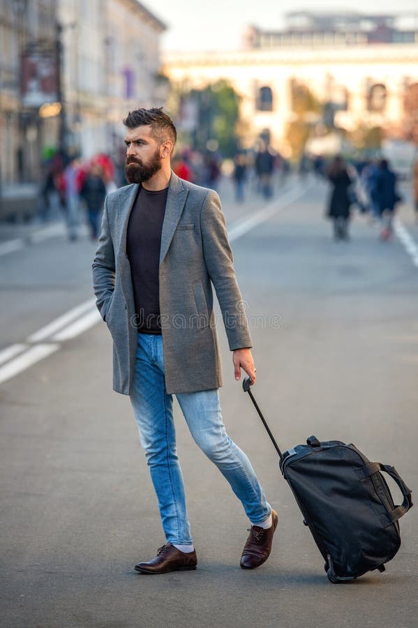 Un homme élégant à cheval marchant et traversant la rue de la ville avec sac de voyage ou valise aller pour un voyage d'affaires images stock
