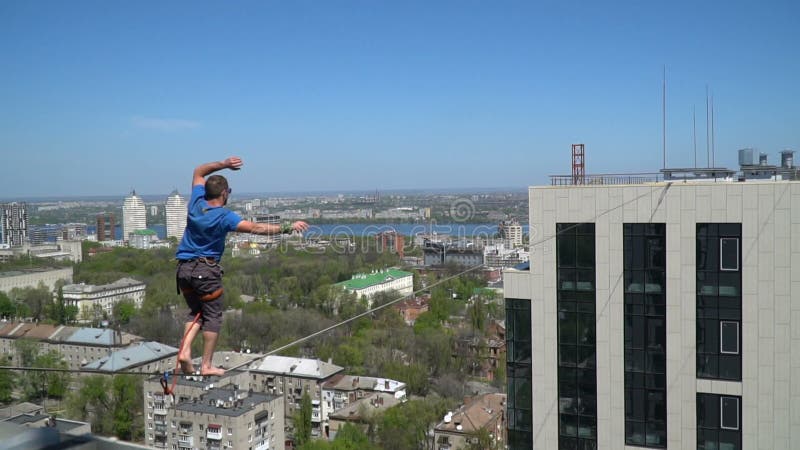 Un homme équilibre sur la corde serrée, une vue de la ville de la taille banque de vidéos