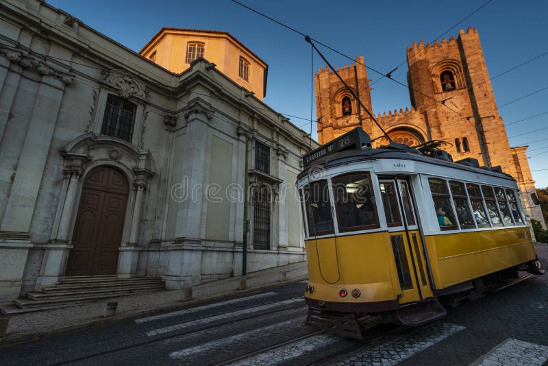 Un iconico tram giallo che passa davanti alla cattedrale di lisbona se de lisboa nella città di lisbo immagini stock libere da diritti