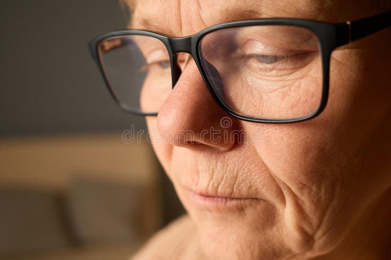 Un individuo con occhiali che mette in evidenza in modo pensieroso espressioni morbide e linee di età. L'atmosfera calda all'inter fotografia stock libera da diritti