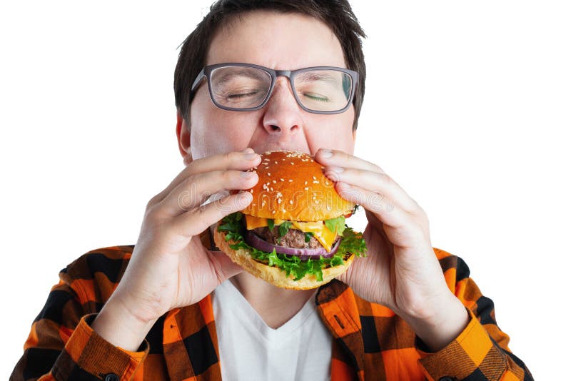 Un individuo joven con los vidrios que sostienen una hamburguesa fresca Un estudiante muy hambriento come los alimentos de prepar fotos de archivo libres de regalías Un individuo joven con los vidrios que sostienen una hamburguesa fresca Un estudiante muy hambriento come los alimentos de prepar fotos de archivo libres de regalías