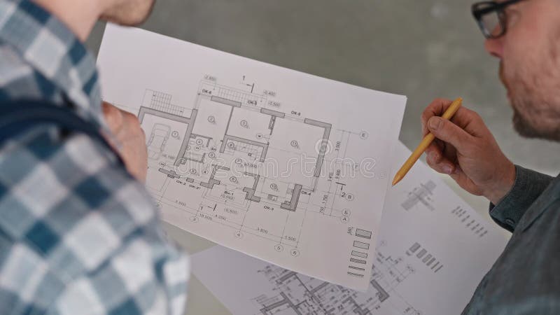 Un ingegnere e un costruttore discutono un progetto immobiliare basato su disegni dettagliati. lavori in un cantiere. sviluppatore stock footage