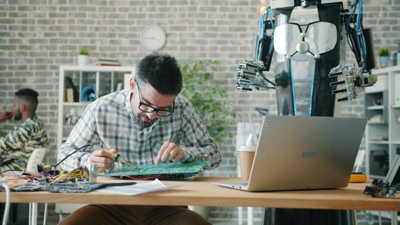 Un ingénieur en robotique qui utilise du fer à souder pour réparer le microcircuit dans la salle de travail