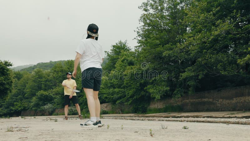 Un jeune couple caucasien une femme et un homme jouent à badminton. vue à angle faible. concept de loisirs d'été banque de vidéos