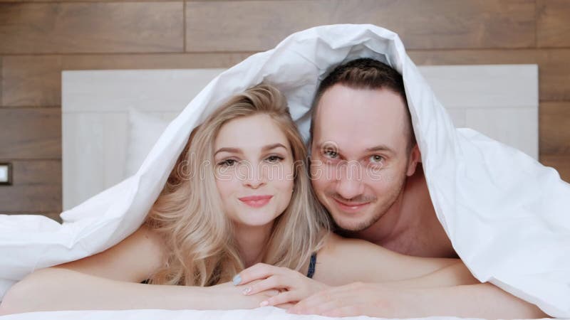 Un jeune couple marié, un homme et une femme sont allongés sur un lit avec du linge de maison blanc Matin et réveil