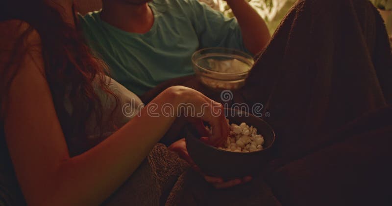 Un jeune couple partage du pop-corn et rit en regardant un film à la maison sur le canapé banque de vidéos