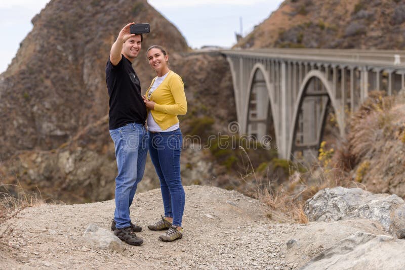 Un jeune couple prend un selfie dans le fron du grand pont de crique, Big Sur, la Californie, Etats-Unis images stock Un jeune couple prend un selfie dans le fron du grand pont de crique, Big Sur, la Californie, Etats-Unis images stock