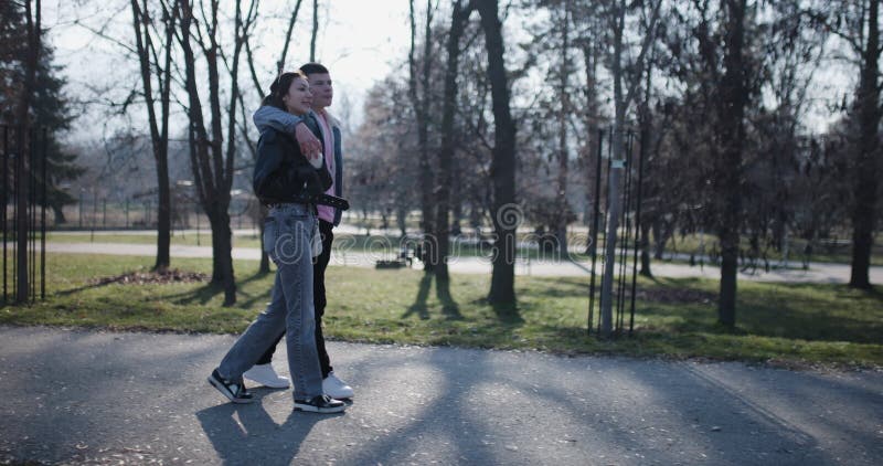 Un jeune couple profite d'une promenade romantique dans un parc ensoleillé qui embrasse la beauté de la nature. banque de vidéos