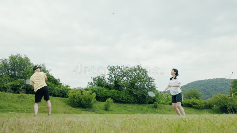 Un jeune couple une femme et un homme jouant à badminton. mouvement lent. concept de loisirs d'été banque de vidéos