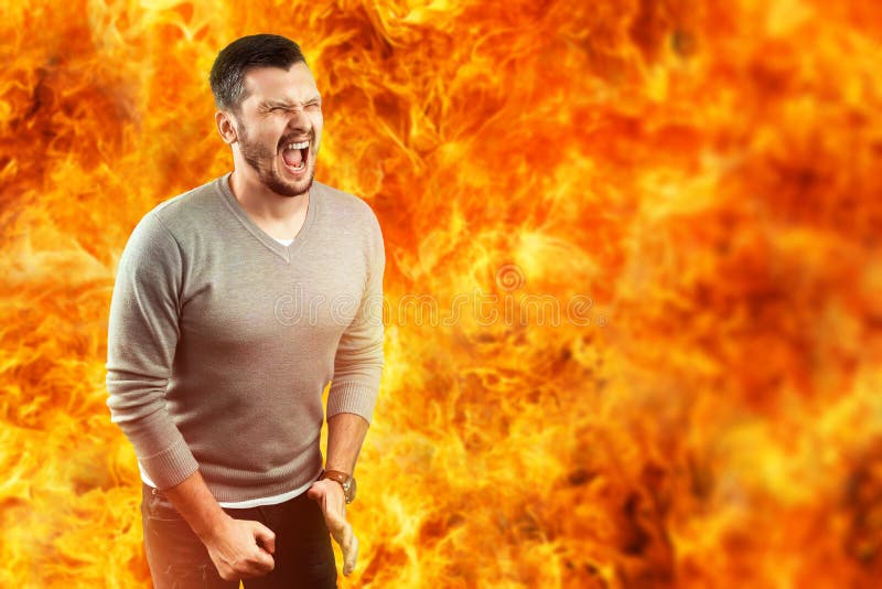 Un jeune homme attirant sent la douleur dans une flamme, entourée par le feu chaud Il sent la haine, colère, colère, envie images stock Un jeune homme attirant sent la douleur dans une flamme, entourée par le feu chaud Il sent la haine, colère, colère, envie images stock