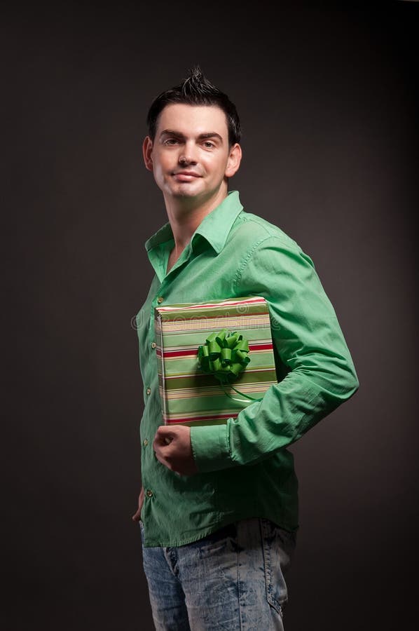 Un jeune homme avec un cadeau dans les mains photographie stock Un jeune homme avec un cadeau dans les mains photographie stock