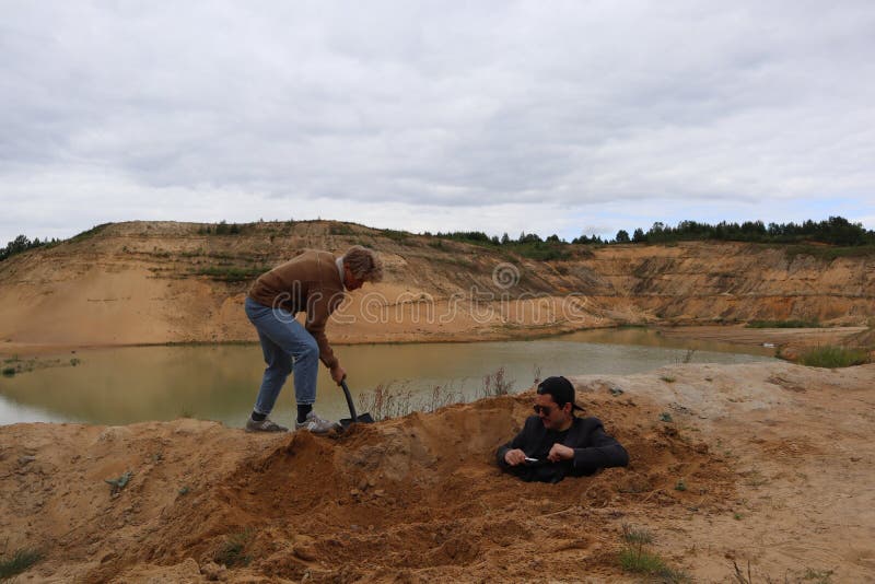 Un jeune homme creuse un trou avec une pelle photographie stock libre de droits Un jeune homme creuse un trou avec une pelle photographie stock libre de droits