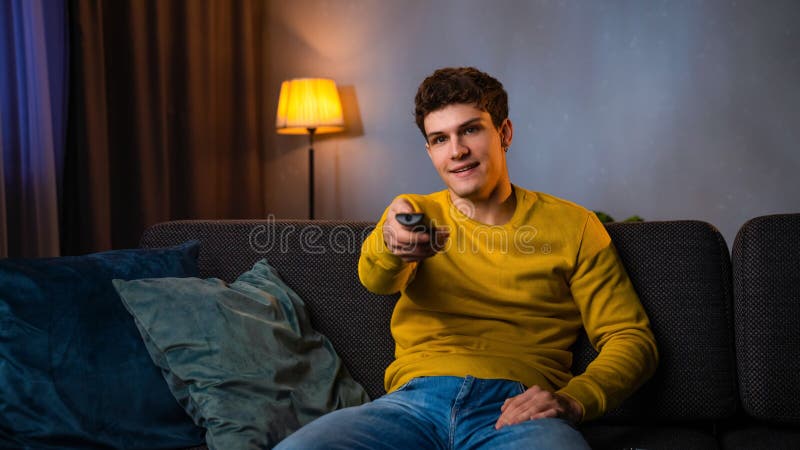 Un jeune homme dans la soirée après le travail se détendre à la maison assis sur le canapé dans le salon regarder programme à la t photo libre de droits