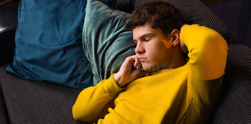 Un jeune homme dans la soirée après le travail se détendre à la maison assis sur le canapé dans le salon regarder la télévision se images libres de droits