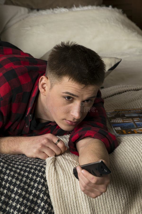 Un jeune homme dans une chemise de hippie se trouve sur un lit photographie stock libre de droits Un jeune homme dans une chemise de hippie se trouve sur un lit photographie stock libre de droits