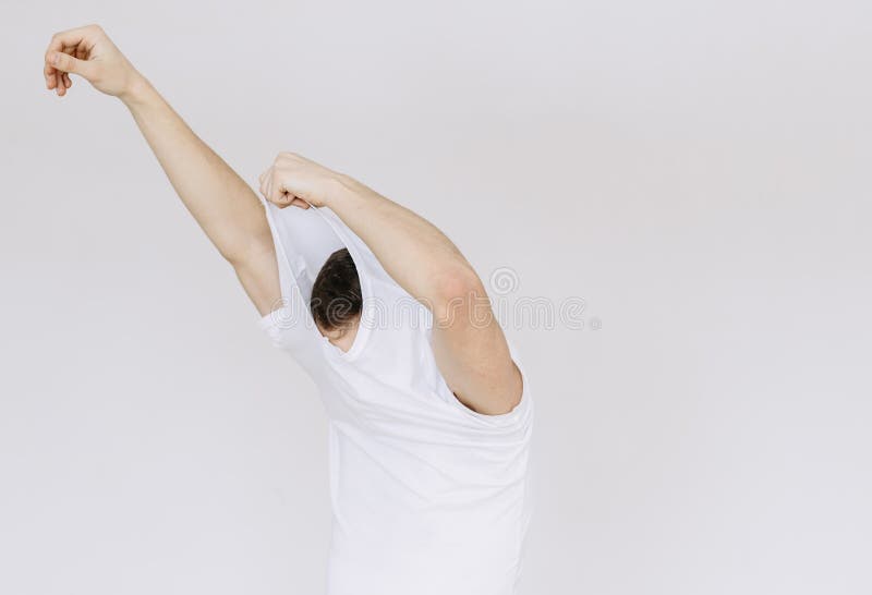 Un jeune homme enlève son T-shirt Fond gris d'isolement photographie stock Un jeune homme enlève son T-shirt Fond gris d'isolement photographie stock
