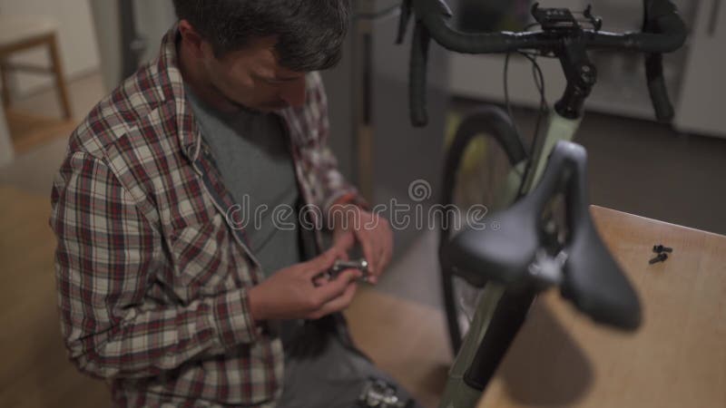 Un Jeune Homme Installe Un Accessoire De Vélo à La Maison Dans Un Studio.  Un Jeune Homme Met Un Vélo à La Maison. Fixation Mâle Clips Vidéos - Vidéo  du garage, gravier