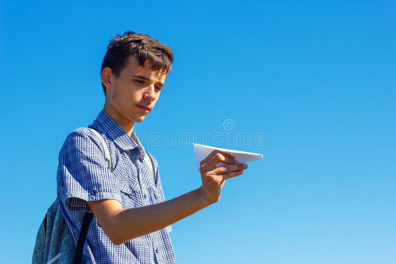Un jeune homme sur un ciel bleu tenant un plan de papier, le concept du vol et le voyage images libres de droits Un jeune homme sur un ciel bleu tenant un plan de papier, le concept du vol et le voyage images libres de droits