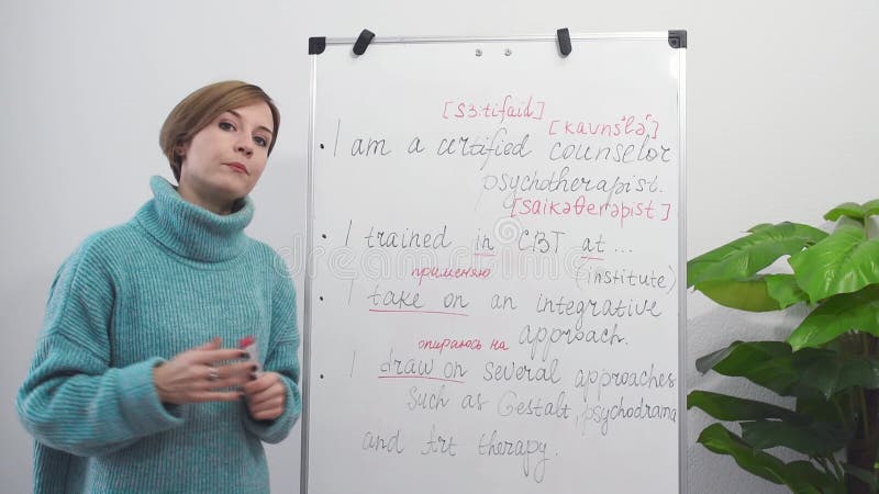 Un jeune professeur d'anglais enregistre une leçon vidéo d'anglais en prenant des notes sur le tableau. éducation en ligne et clips vidéos