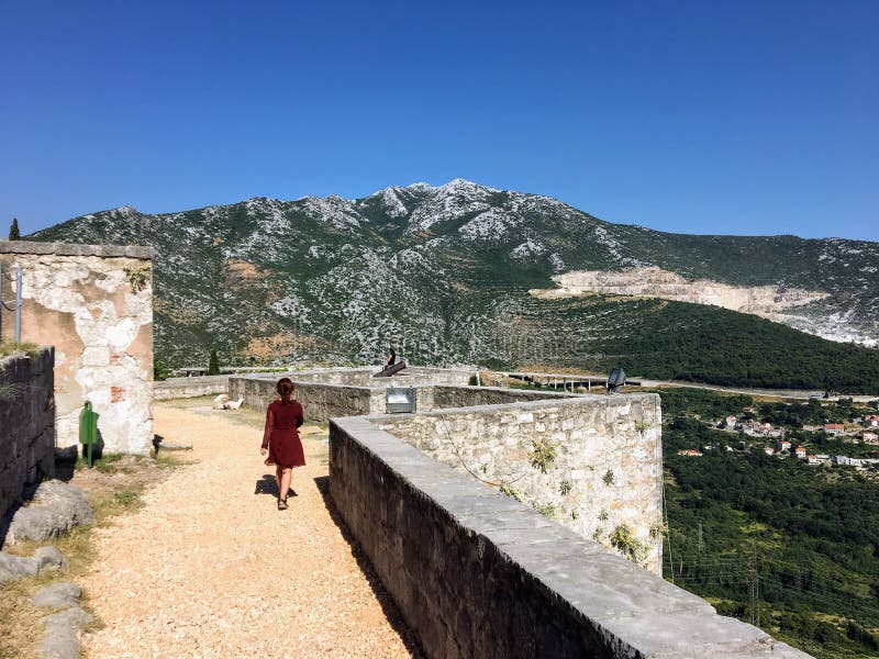 Un jeune touriste féminin marchant autour de la forteresse médiévale de Klis un beau jour d'été photographie stock libre de droits Un jeune touriste féminin marchant autour de la forteresse médiévale de Klis un beau jour d'été photographie stock libre de droits