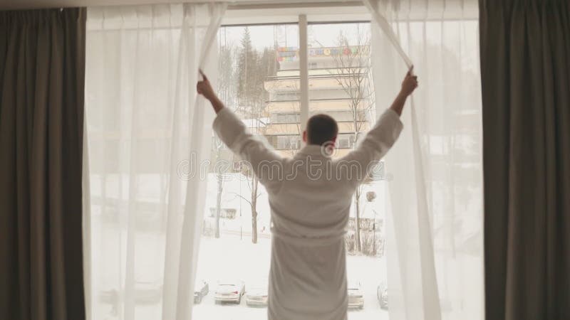 Un joven apuesto se despierta en la mañana y se sale de la cama en el dormitorio que está listo para los negocios metrajes