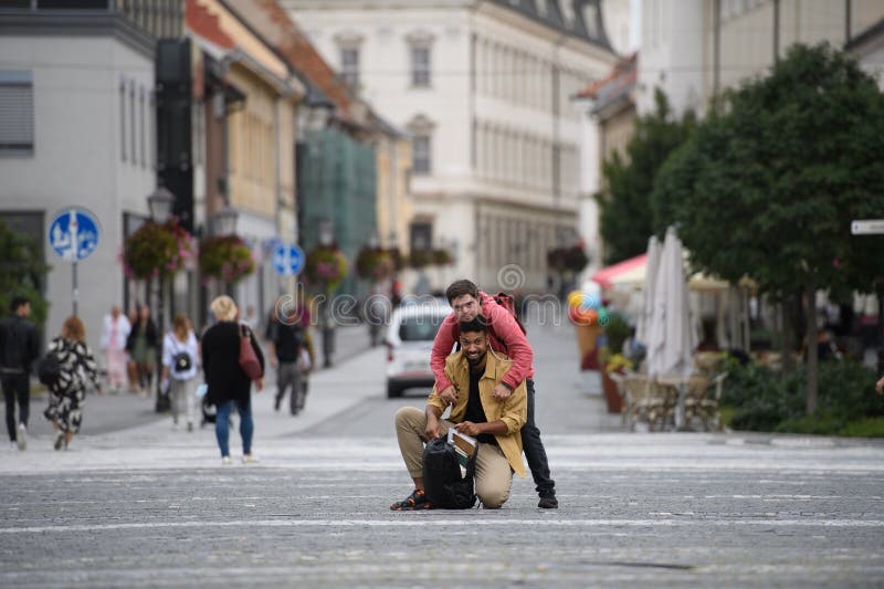 Un joven con síndrome de Down y su amigo mentor caminando por la ciudad hablando. imagen de archivo libre de regalías