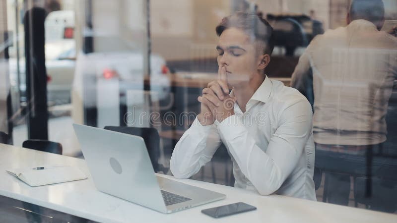 Un joven empresario serio sentado en una mesa de una cafetería que trabaja con una laptop. comunicación independiente con éxito