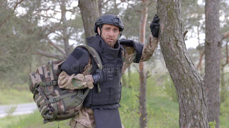 Un hombre con uniforme militar y chaleco antibalas trabaja en el bosque  para desminar el territorio